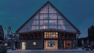 Das Foto zeigt eine Scheune bei Nacht. Von innen scheint Licht durch die Fenster und den Giebel, der mit einer transparenten Fassade versehen ist. Kachel Vorschau