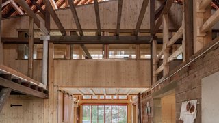 Das Foto zeigt den Innenraum einer Scheune mit Satteldach. Ein Einbau aus Holz sieht aus wie ein kleineres Haus in der Scheune. Kachel Vorschau