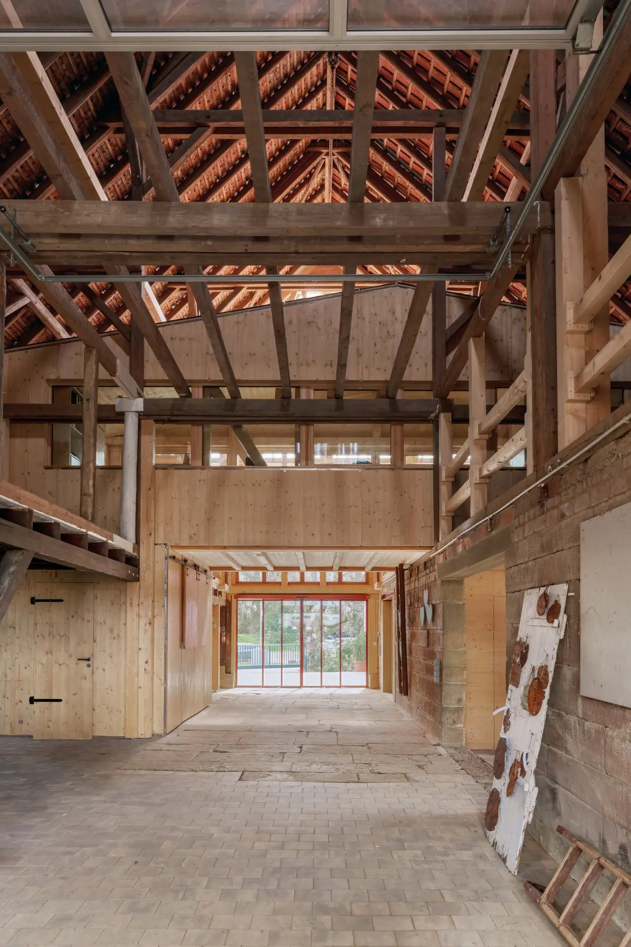 Das Foto zeigt den Innenraum einer Scheune mit Satteldach. Ein Einbau aus Holz sieht aus wie ein kleineres Haus in der Scheune.